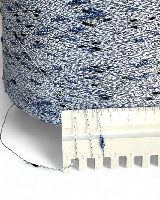 Close-up of a spool of blue and gray yarn with a ruler for scale.