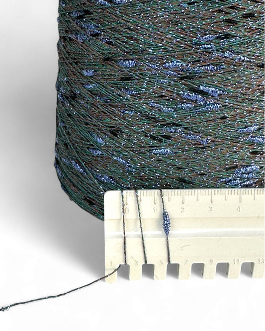 Close-up of a spool of green thread with a ruler for scale on a white background