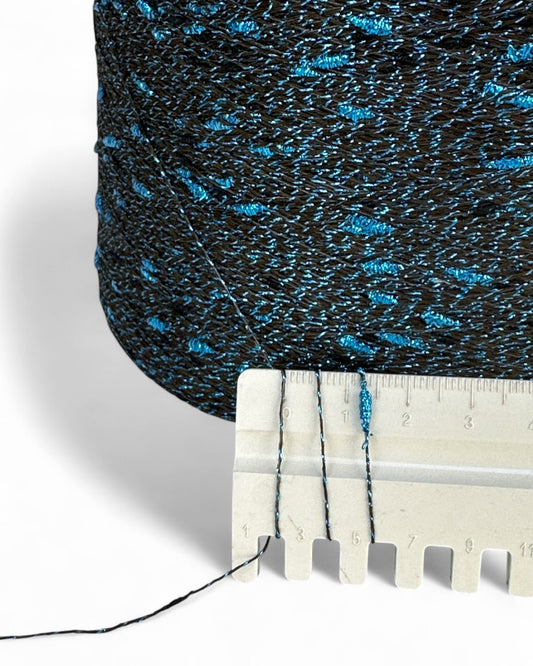 Close-up of textured blue and black fabric with a ruler for scale on a white background