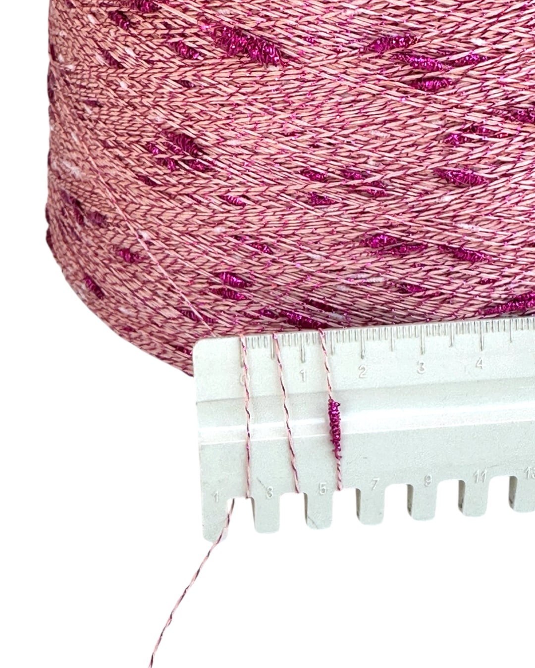Close-up of pink yarn with a measuring tool on a white background