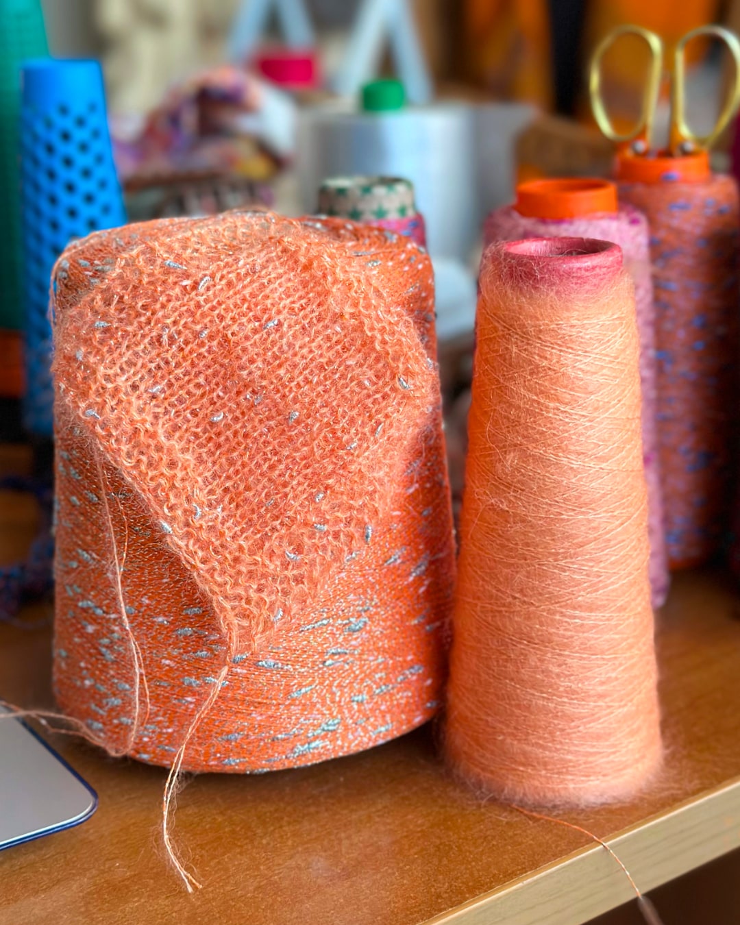 Two spools of orange thread on a wooden surface with blurred background