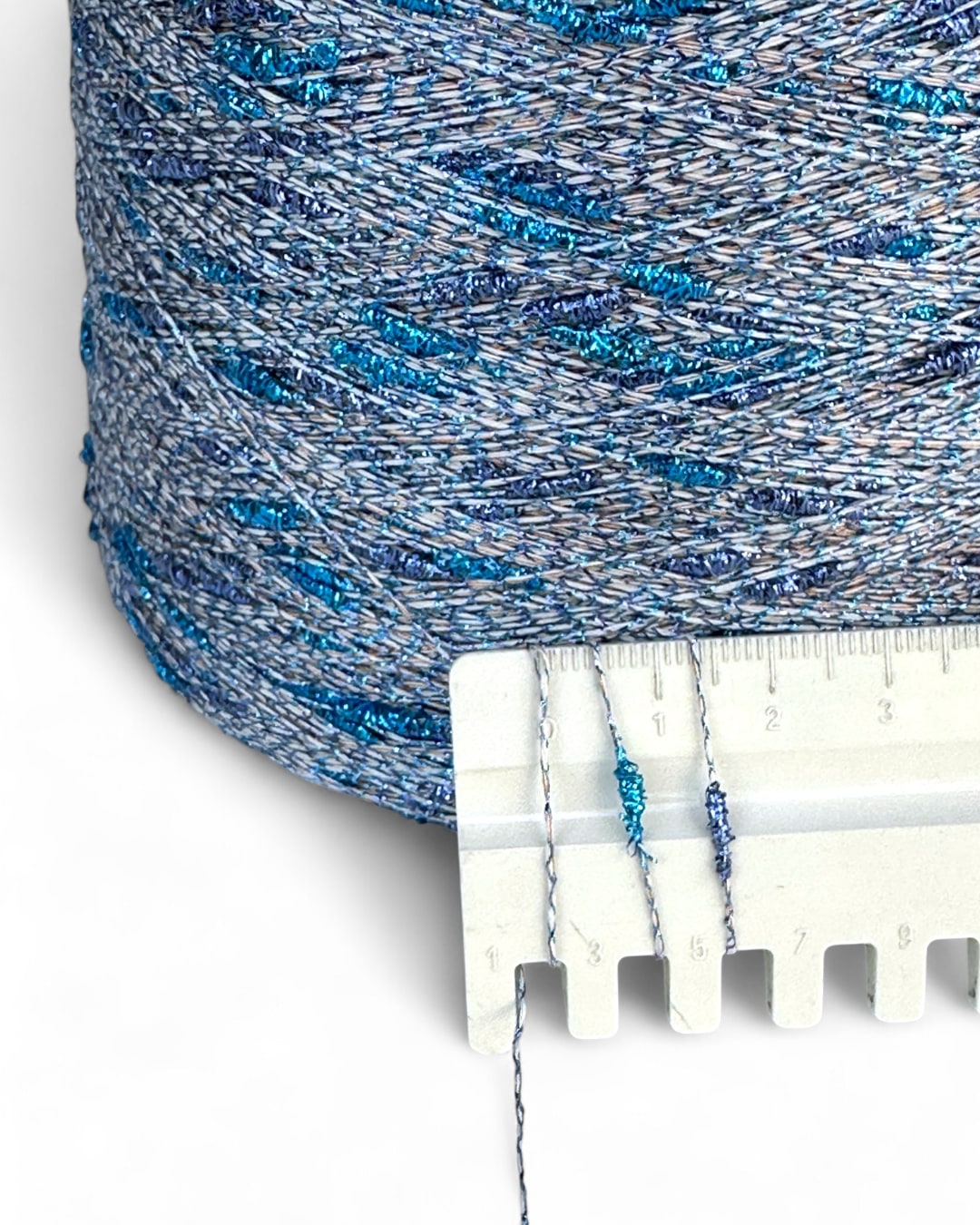Close-up of blue and gray textured fabric with a white plastic strip and measurement scale.