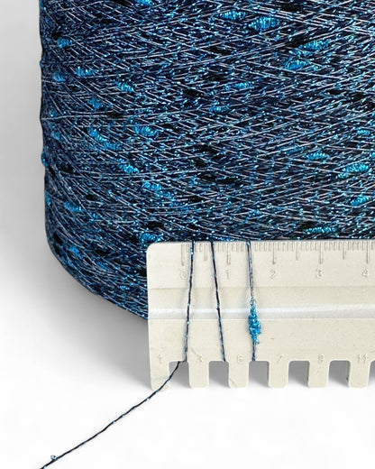 Spool of blue thread with a ruler for scale on a white background