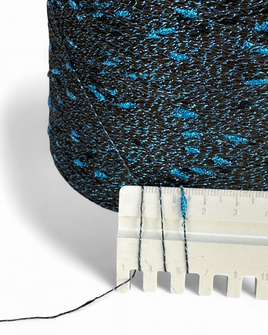 Close-up of textured blue and black fabric with a ruler for scale on a white background