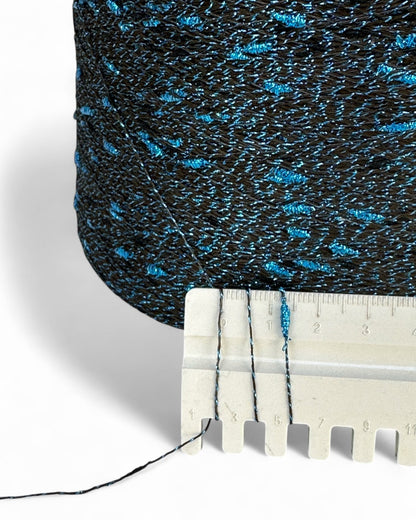 Close-up of textured blue and black fabric with a ruler for scale on a white background