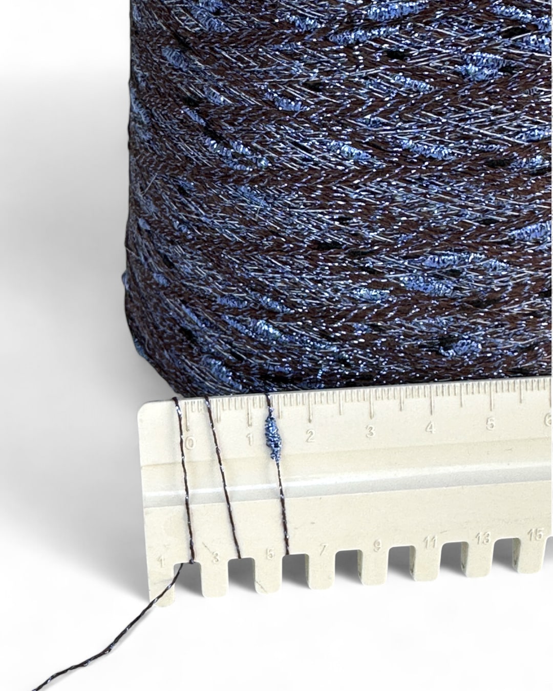 Spool of blue thread with a ruler for scale on a white background