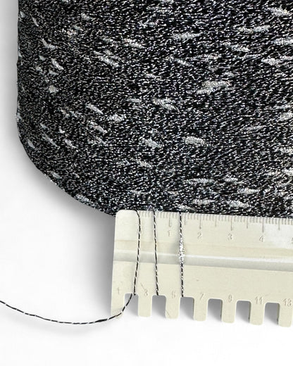 Close-up of textured black and gray fabric with a ruler for scale on a white background