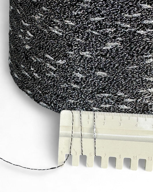 Close-up of textured black and gray fabric with a ruler for scale on a white background