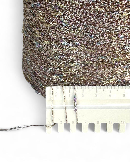 Close-up of metallic thread with a ruler for scale on a white background