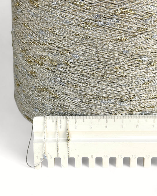 Close-up of a spool of glittery thread with a ruler for scale on a white background