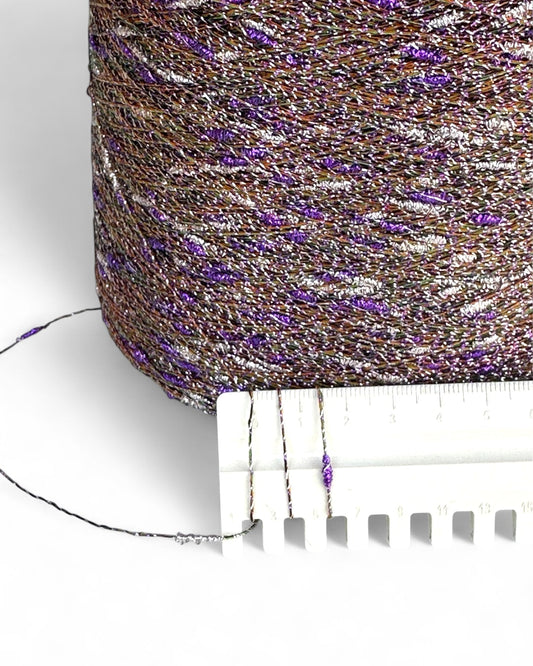 Close-up of a spool of glittery thread with a measuring tape for scale.