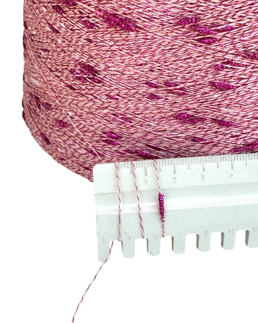 Close-up of pink yarn with a measuring tool on a white background