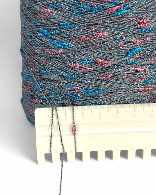 Spool of multicolored thread with a ruler for scale on a white background