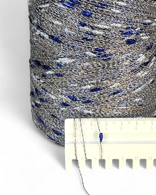 Close-up of a spool of blue and gray thread with a ruler for scale on a white background