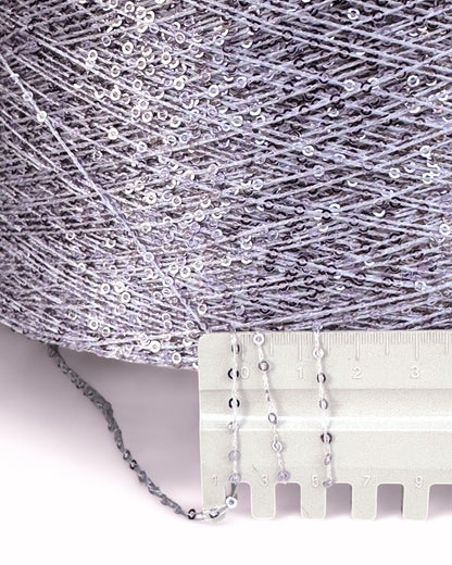 Close-up of silver sequin fabric with a measuring tool on a white background
