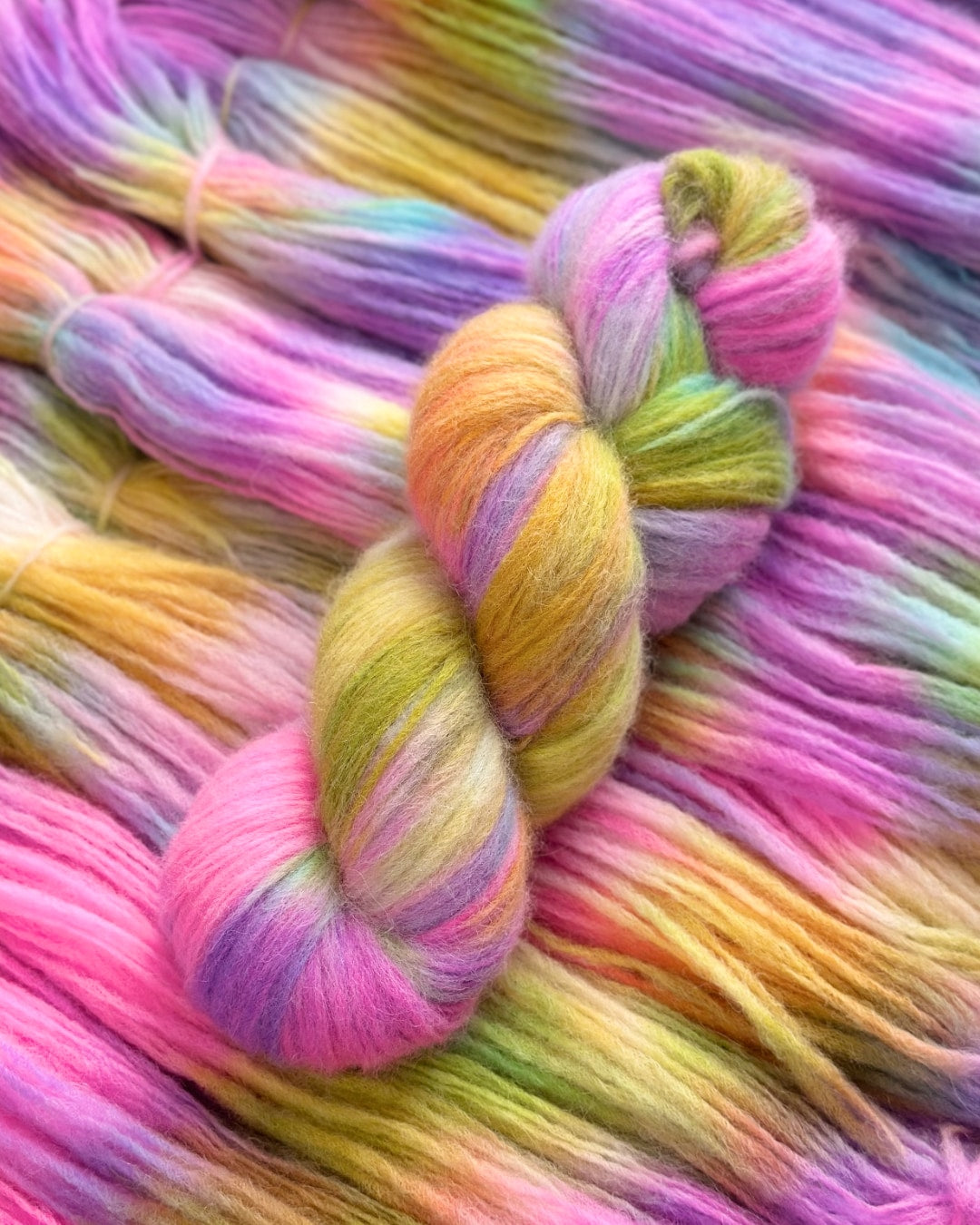 Luxurious super baby alpaca and merino wool blend yarn with nylon for strength, 400m per 100g. Featuring a vibrant mix of pink, purple, yellow, and green hues for an eye-catching variegated effect. Perfect for knitting or crocheting soft and warm garments.