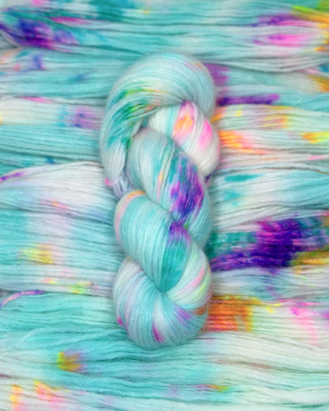 Soft merino wool mix hand-dyed yarn featuring turquoise, pink, purple splashes on white base.