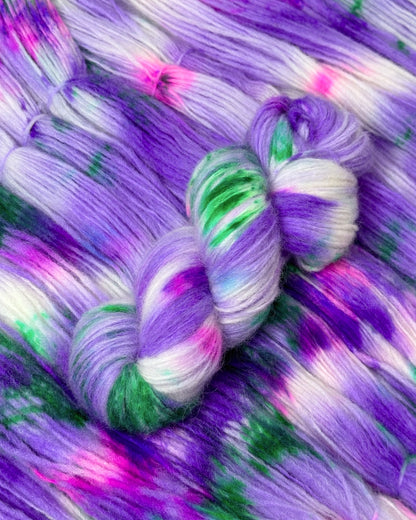 Artisanal multi-colored yarn featuring a rich palette of purples complemented by green highlights and specks of pink; super baby alpaca with merino wool mix.